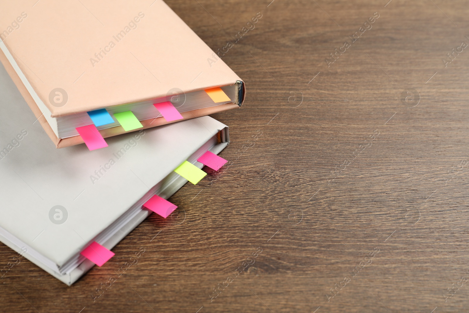 Photo of Books with colorful tabs on wooden table, closeup. Space for text