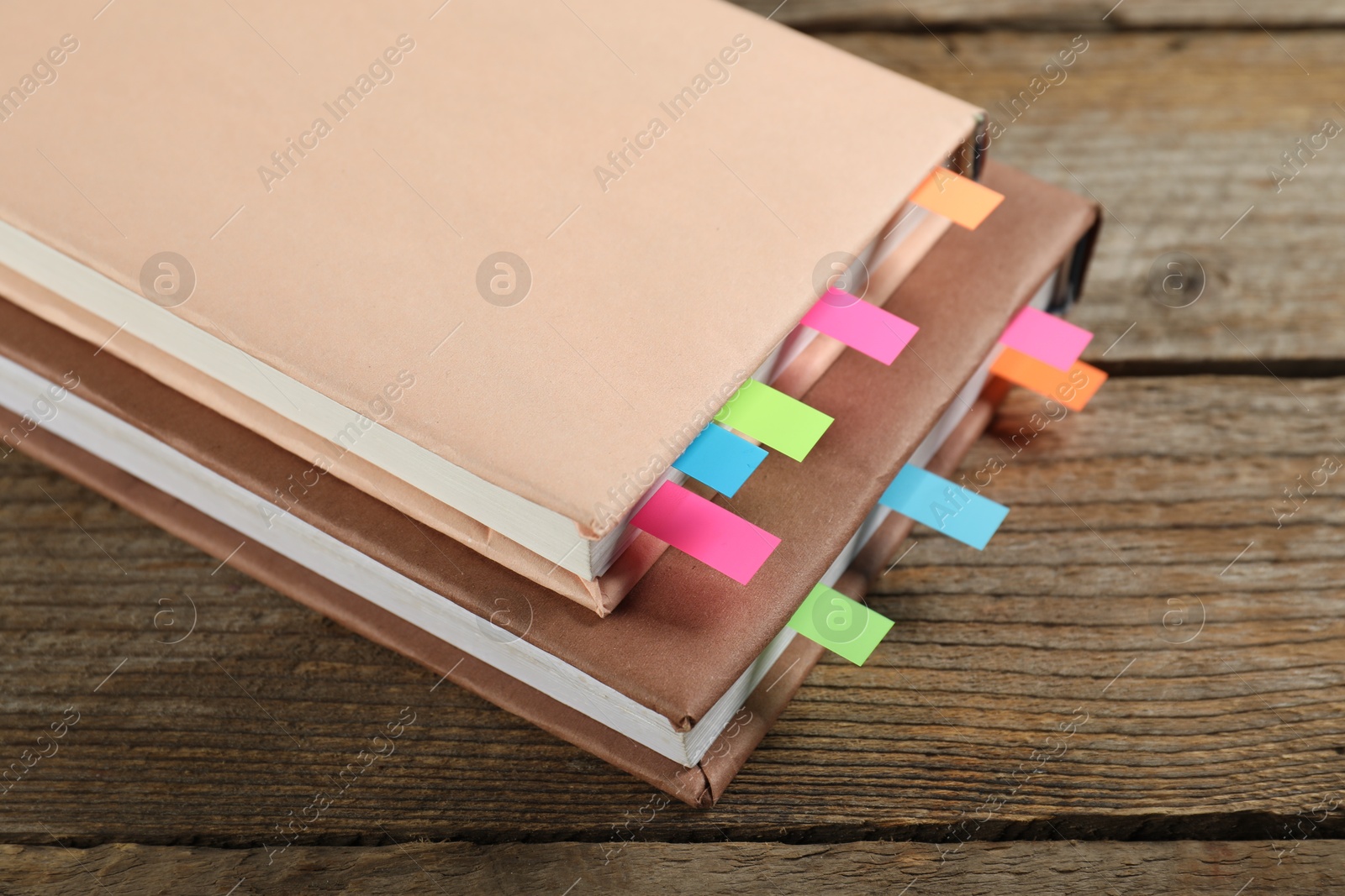 Photo of Books with colorful tabs on wooden table, closeup