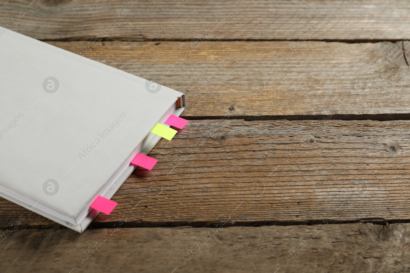 Photo of Book with colorful tabs on wooden table, closeup. Space for text