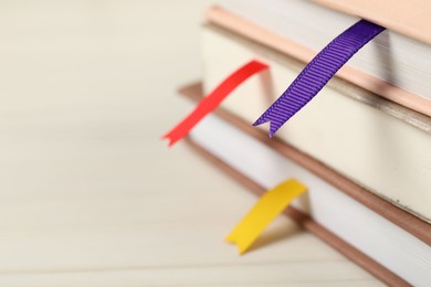 Photo of Books with ribbon bookmarks on light wooden table, closeup. Space for text