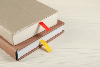 Photo of Books with ribbon bookmarks on light wooden table, closeup. Space for text