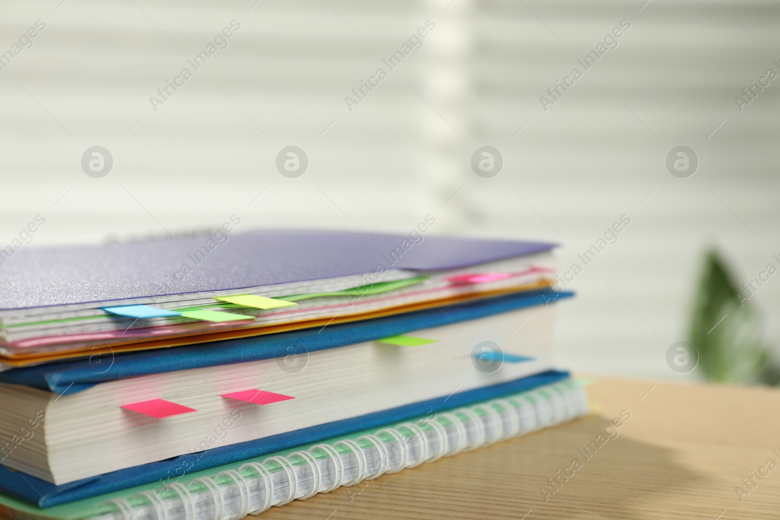 Photo of Notebooks and book with colorful tabs on wooden table indoors, closeup