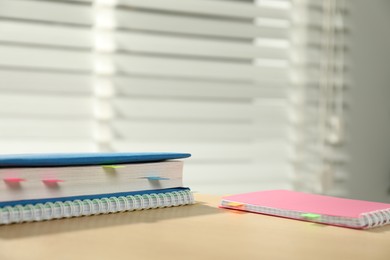 Photo of Book and notebooks with colorful tabs on wooden table indoors, space for text