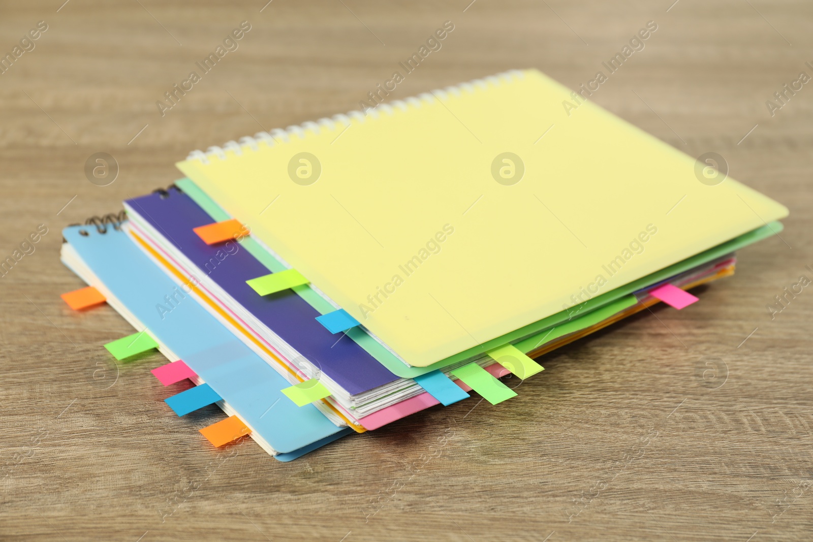 Photo of Notebooks with colorful tabs on wooden table, closeup