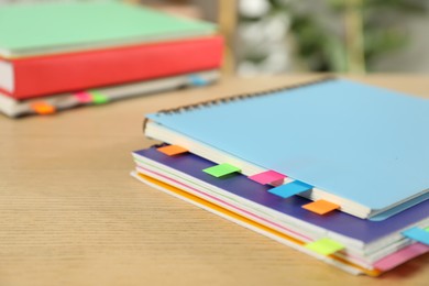 Photo of Notebooks with colorful tabs on wooden table, closeup