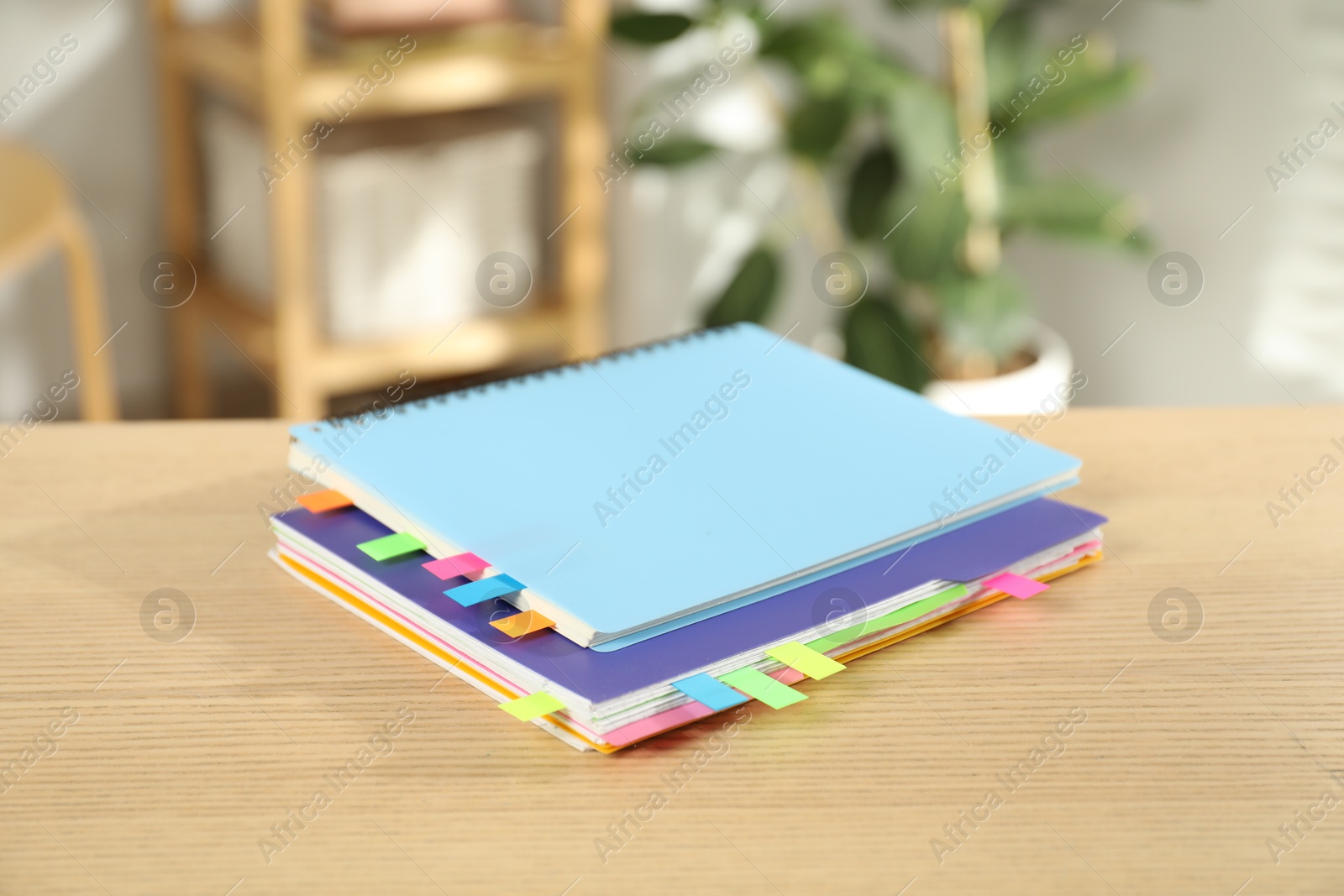 Photo of Notebooks with colorful tabs on wooden table indoors