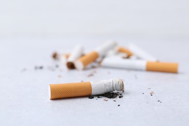 Photo of Cigarette butts on light background, selective focus