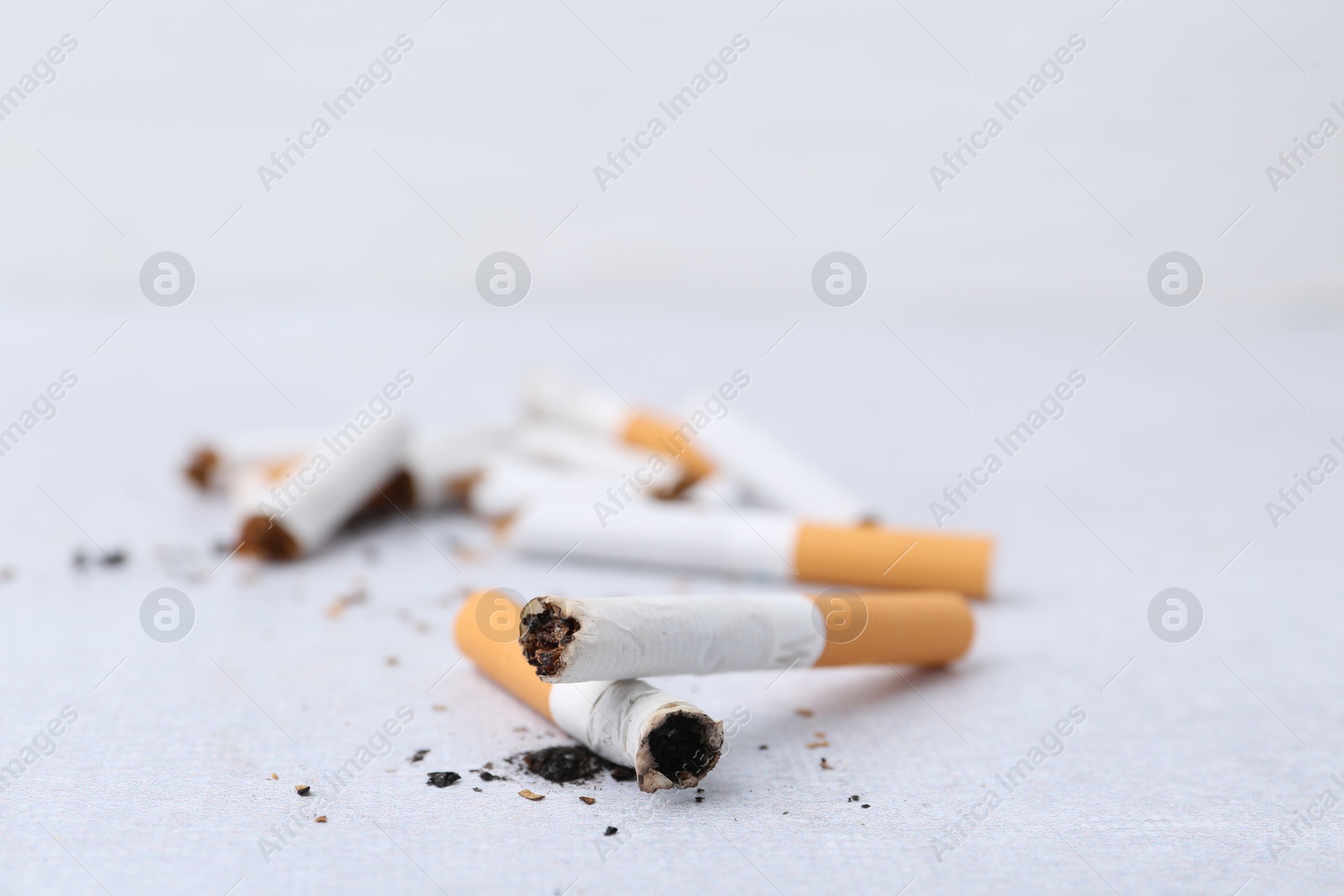 Photo of Many cigarette butts on light background, closeup