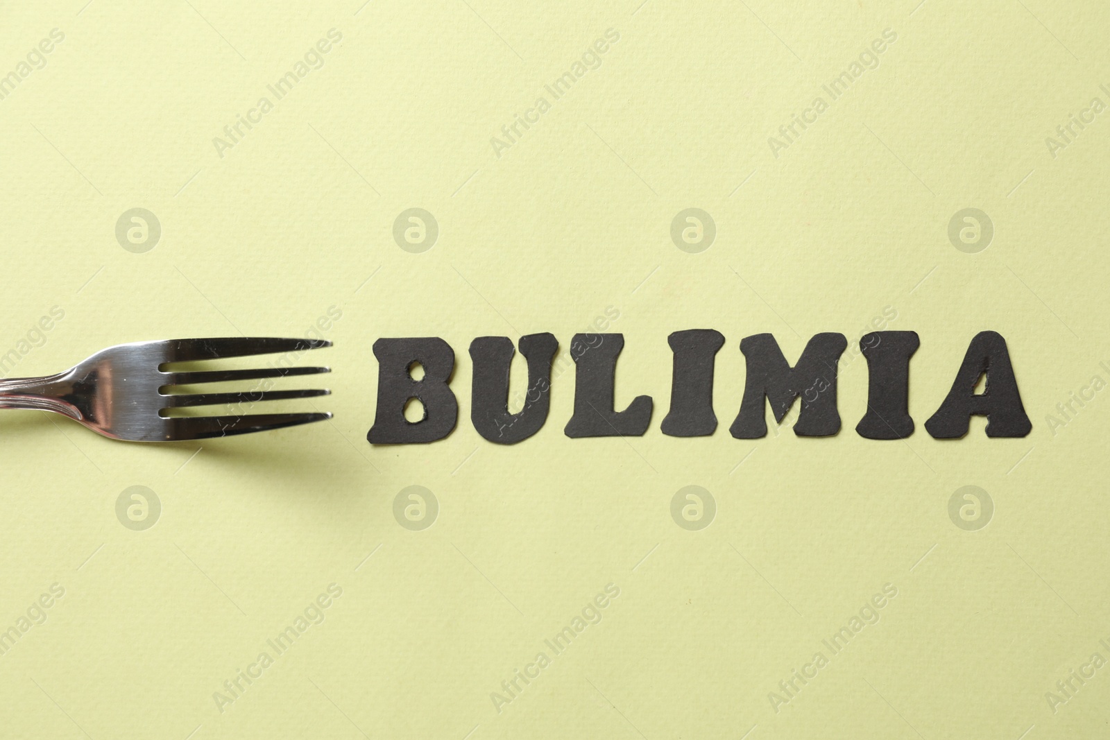 Photo of Word Bulimia and fork on olive background, top view