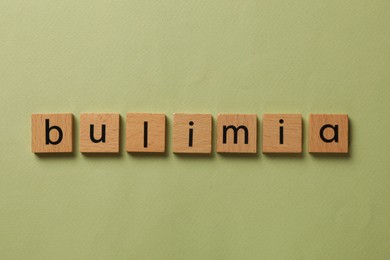 Photo of Word Bulimia on olive background, top view