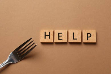 Photo of Bulimia. Word Help and fork on brown background, top view