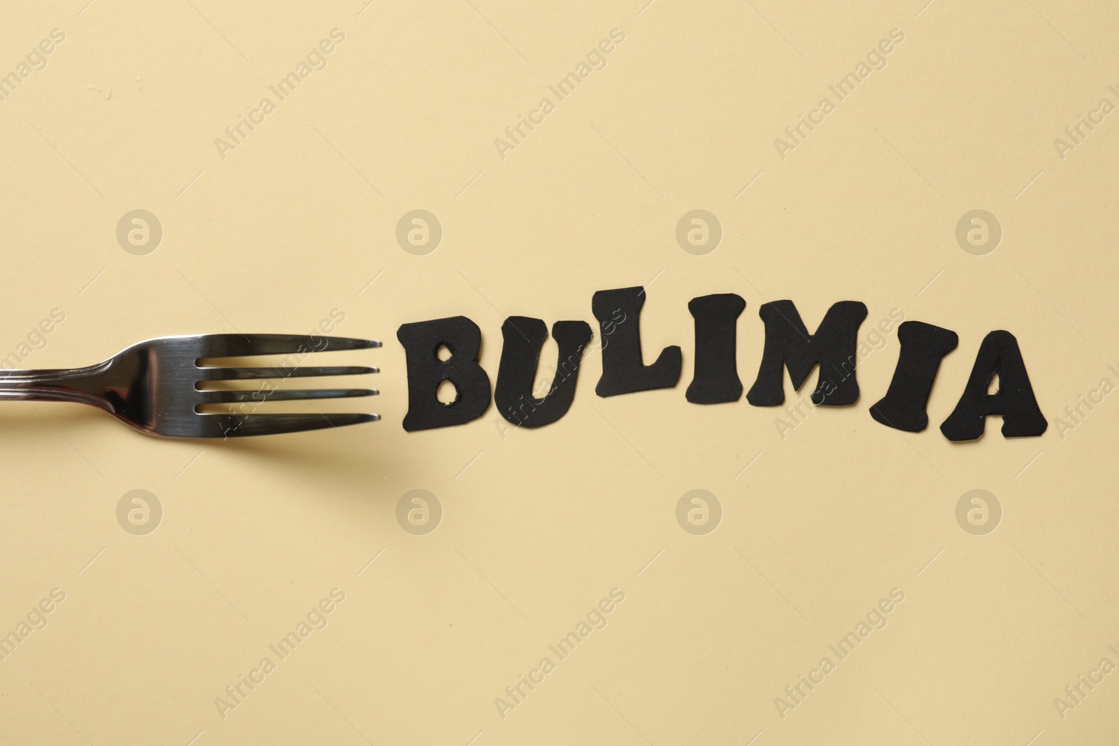 Photo of Word Bulimia and fork on beige background, top view