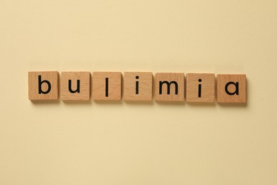 Photo of Word Bulimia on beige background, top view