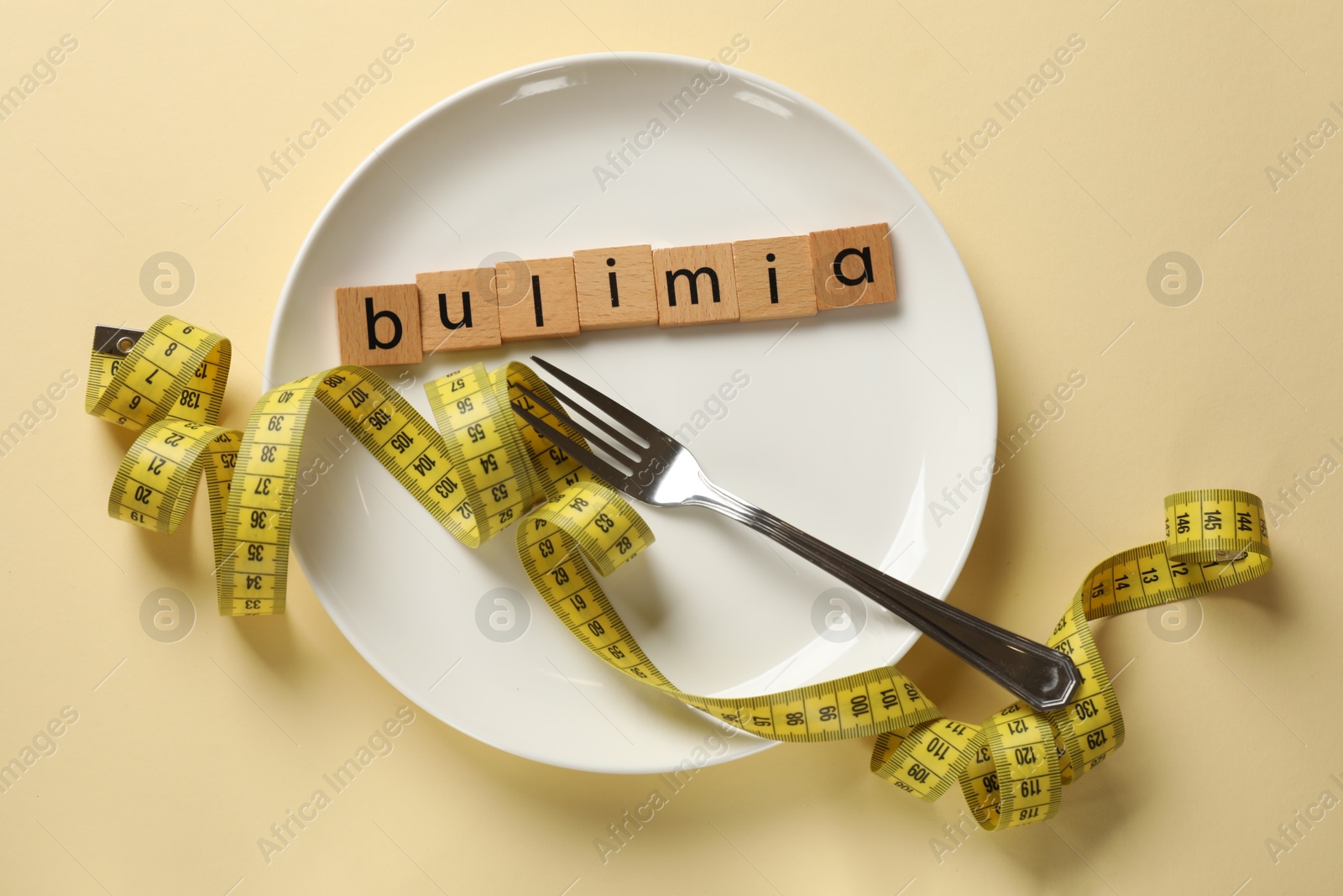 Photo of Plate with word Bulimia, fork and measuring tape on beige background, top view