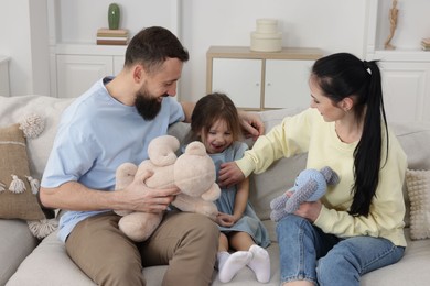 Photo of Cute little girl and her parents spending time together at home