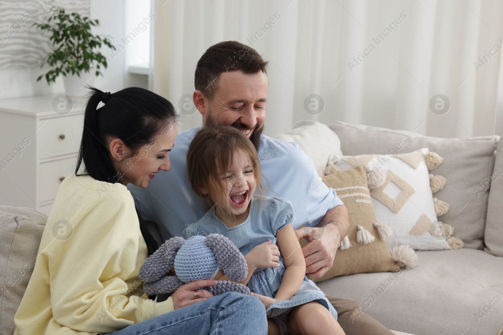 Photo of Cute little girl and her parents spending time together at home