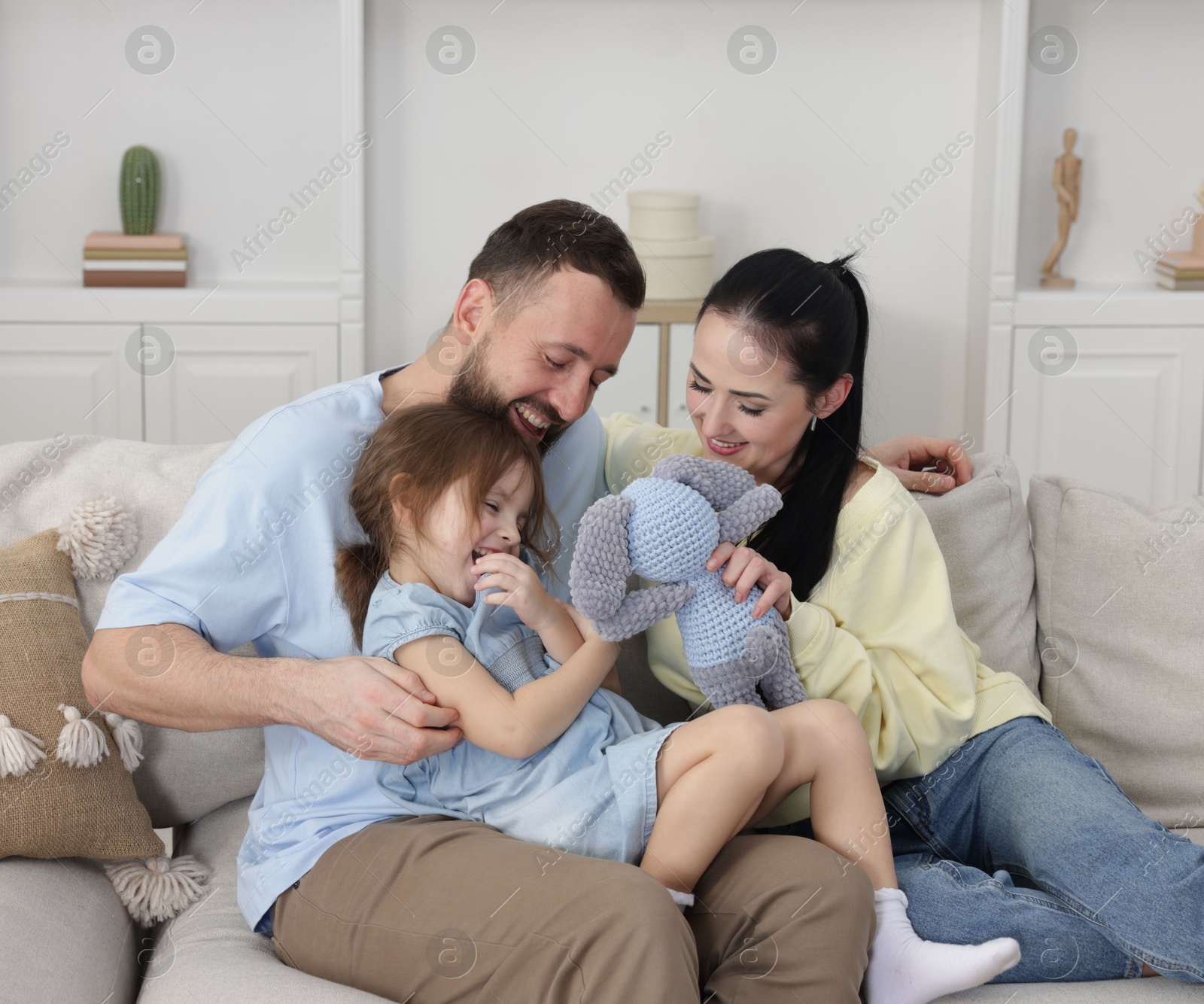 Photo of Cute little girl and her parents spending time together at home