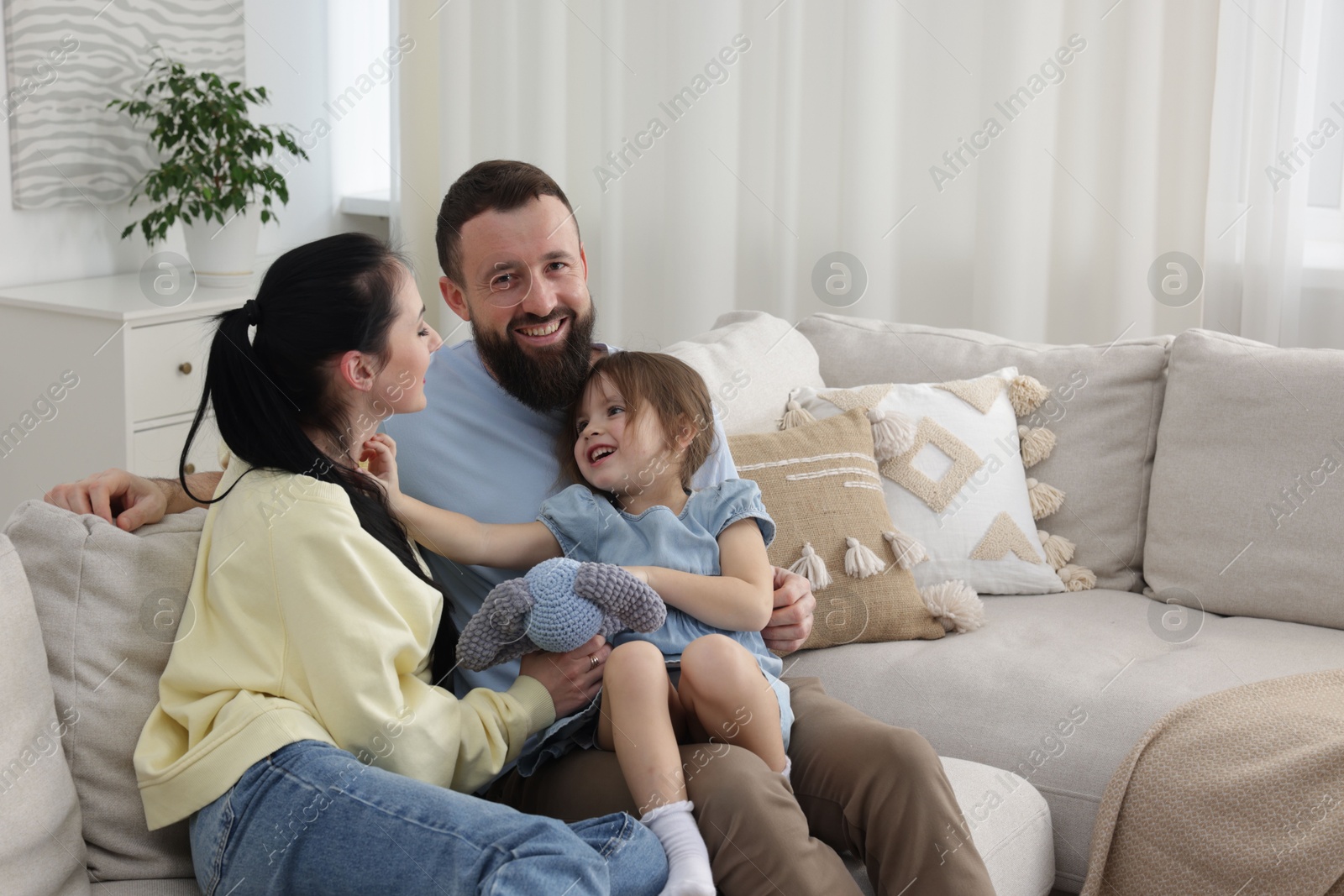 Photo of Cute little girl and her parents spending time together at home