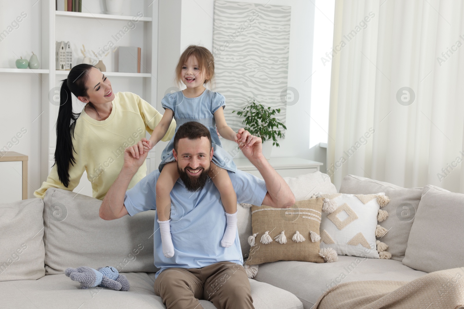 Photo of Cute little girl and her parents having fun at home