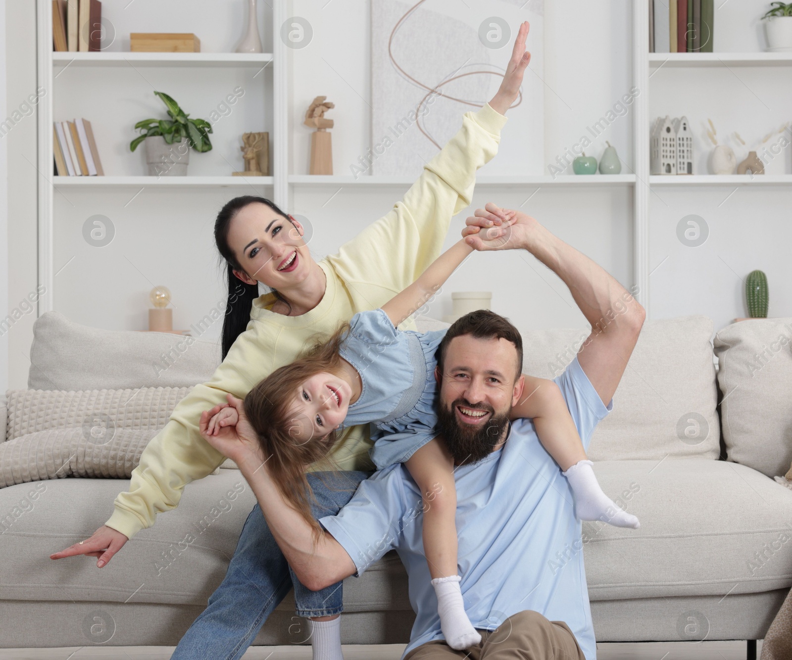 Photo of Cute little girl and her parents having fun at home