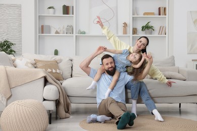 Photo of Cute little girl and her parents having fun at home