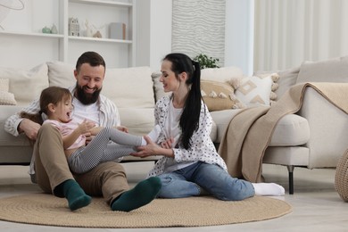 Photo of Cute little girl and her parents having fun at home