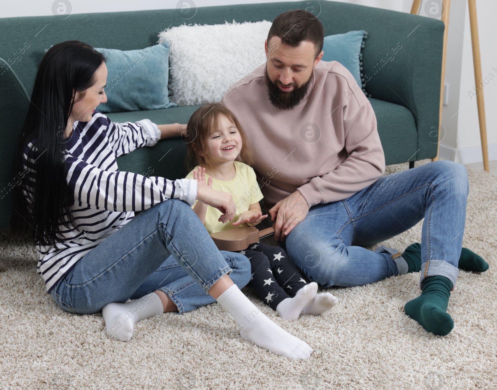 Photo of Parents and their cute little daughter playing ukulele at home