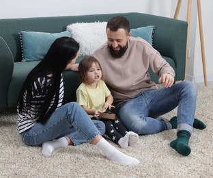 Photo of Parents and their cute little daughter playing ukulele at home