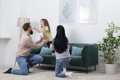 Photo of Cute little girl and her parents having fun at home