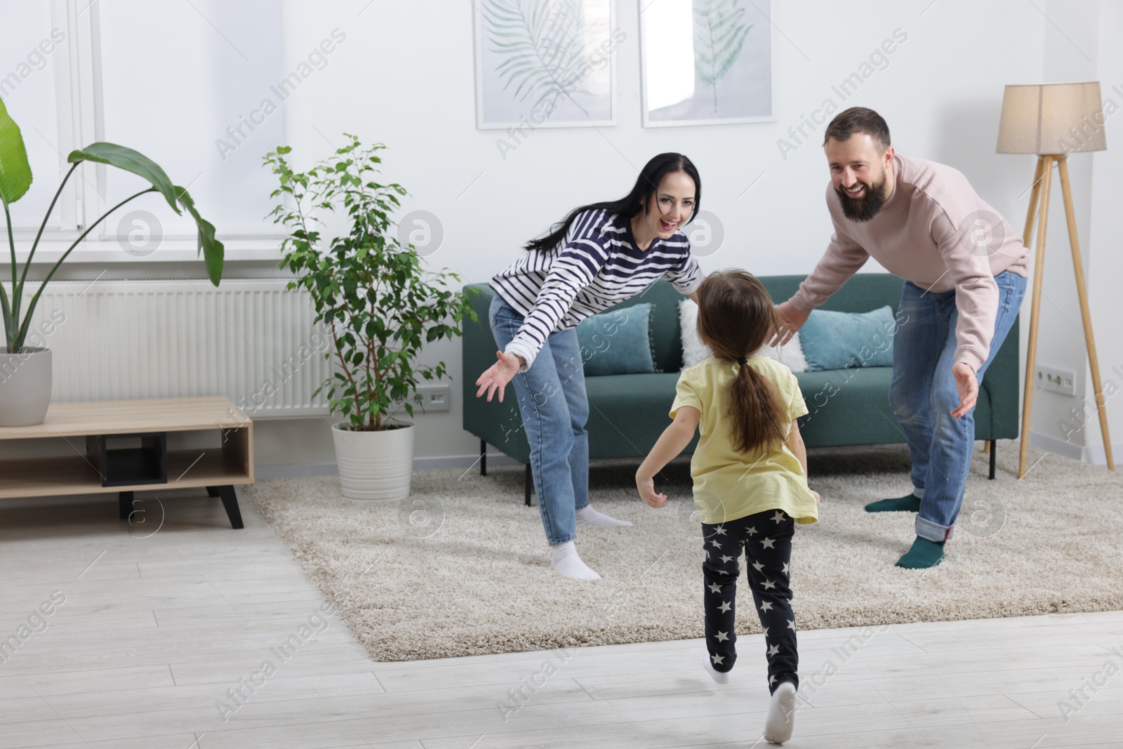 Photo of Cute little girl and her parents having fun at home