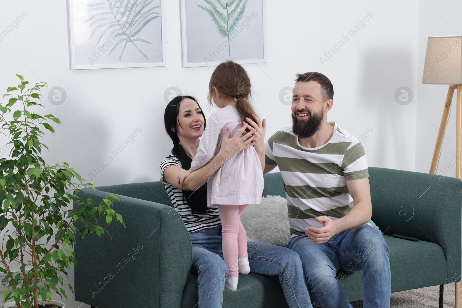 Photo of Cute little girl and her parents having fun at home