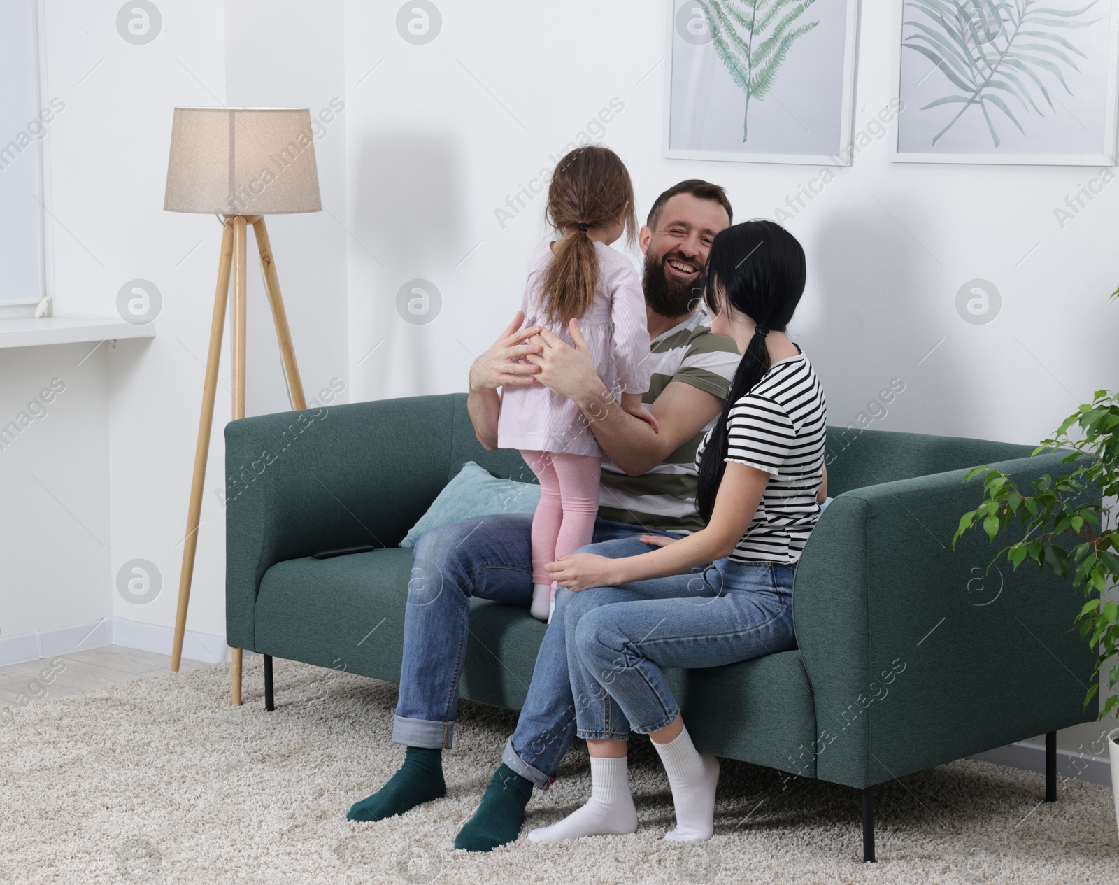 Photo of Cute little girl and her parents having fun at home