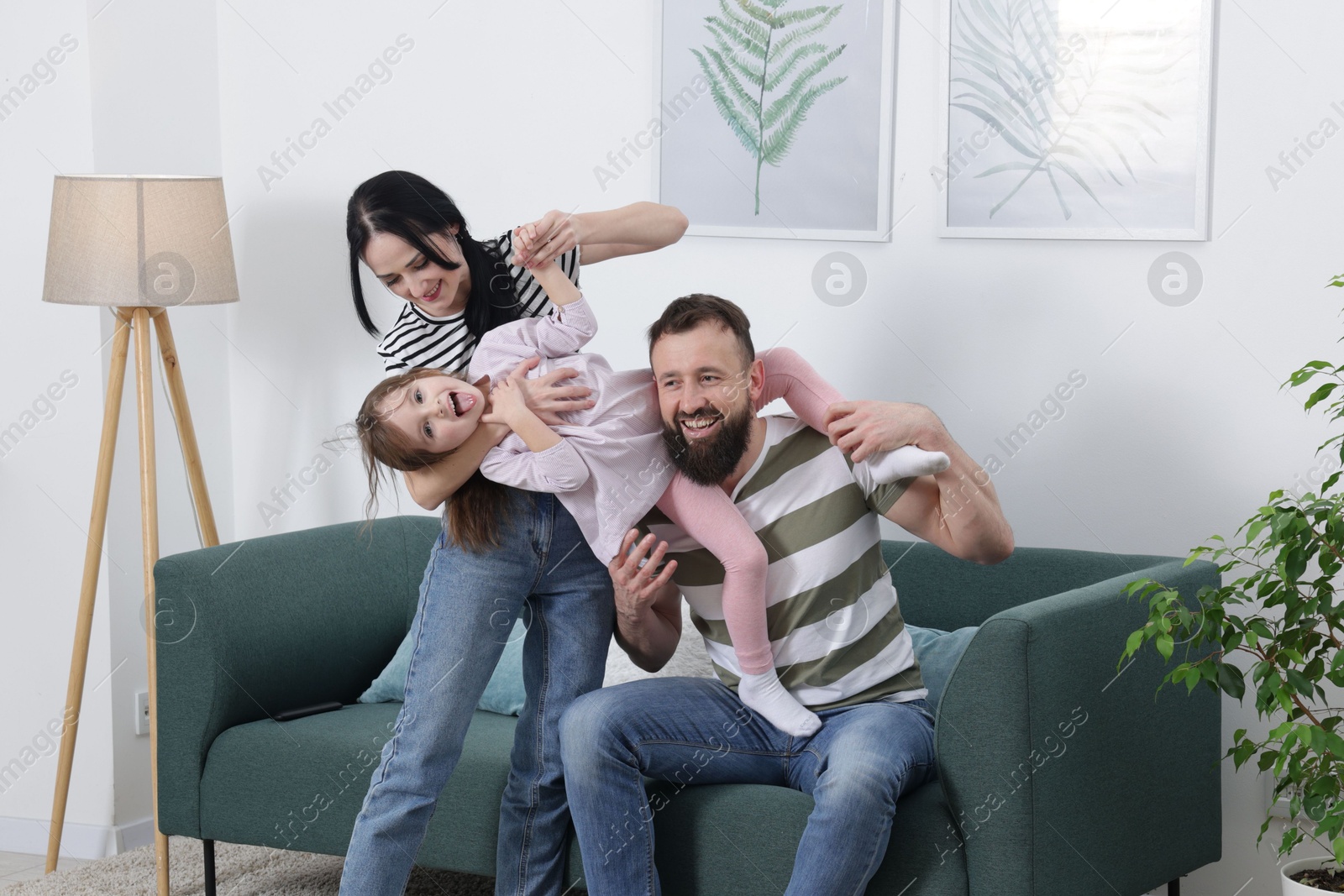 Photo of Cute little girl and her parents having fun at home