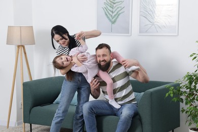 Photo of Cute little girl and her parents having fun at home