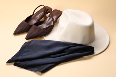 Photo of Stylish handkerchief, hat and shoes on beige background, closeup