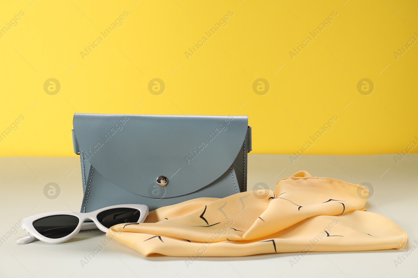 Photo of Leather handbag, handkerchief and sunglasses on color background