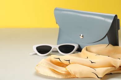 Photo of Leather handbag, handkerchief and sunglasses on color background, closeup. Space for text