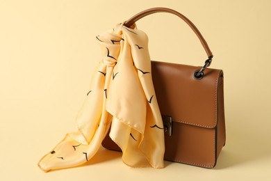 Photo of Leather bag with handkerchief on beige background, closeup