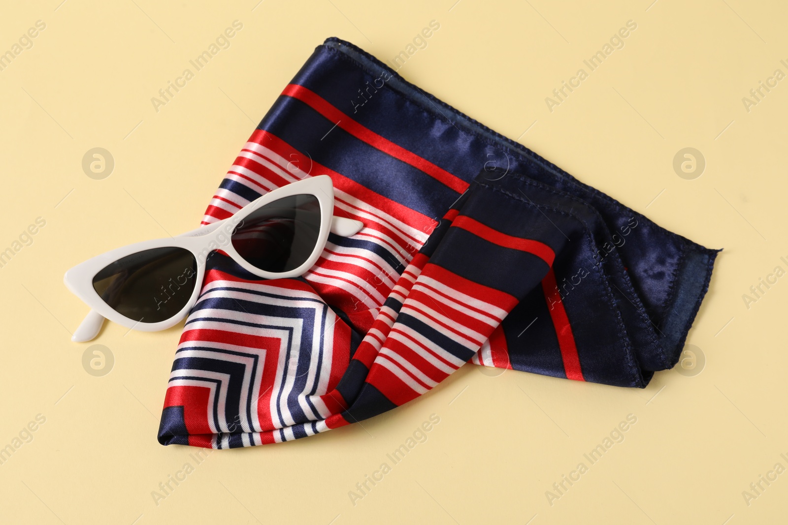 Photo of Stylish handkerchief and sunglasses on beige background, top view