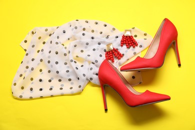 Photo of Stylish scarf, earrings and high heeled shoes on yellow background, flat lay