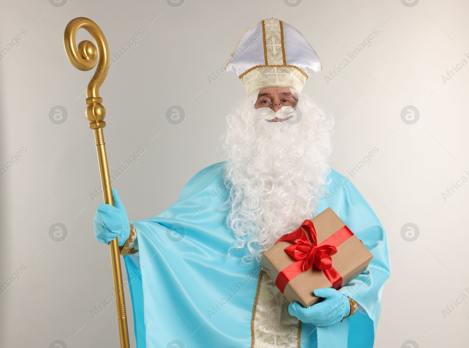 Photo of Saint Nicholas with Christmas gift and crozier on gray background