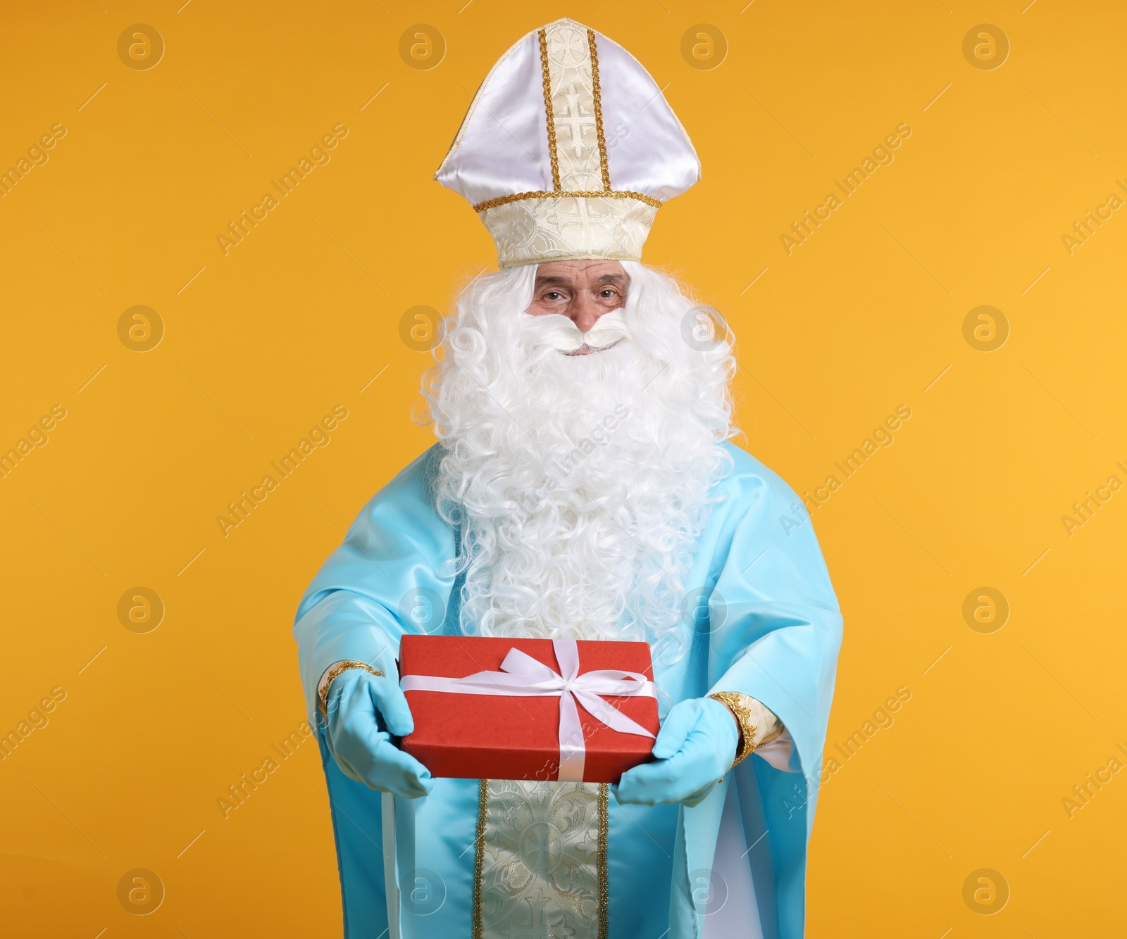 Photo of Saint Nicholas with Christmas gift on orange background