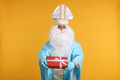 Photo of Saint Nicholas with Christmas gift on orange background