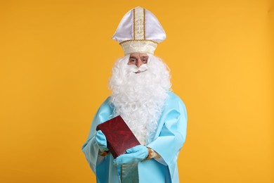 Photo of Saint Nicholas with book on orange background