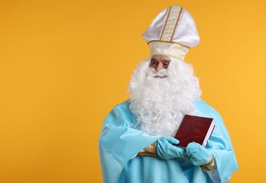 Photo of Saint Nicholas with book on orange background, space for text