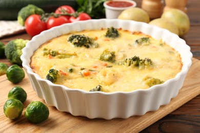 Photo of Delicious vegetable casserole and ingredients on wooden table, closeup