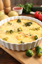 Photo of Delicious vegetable casserole and ingredients on wooden table, closeup