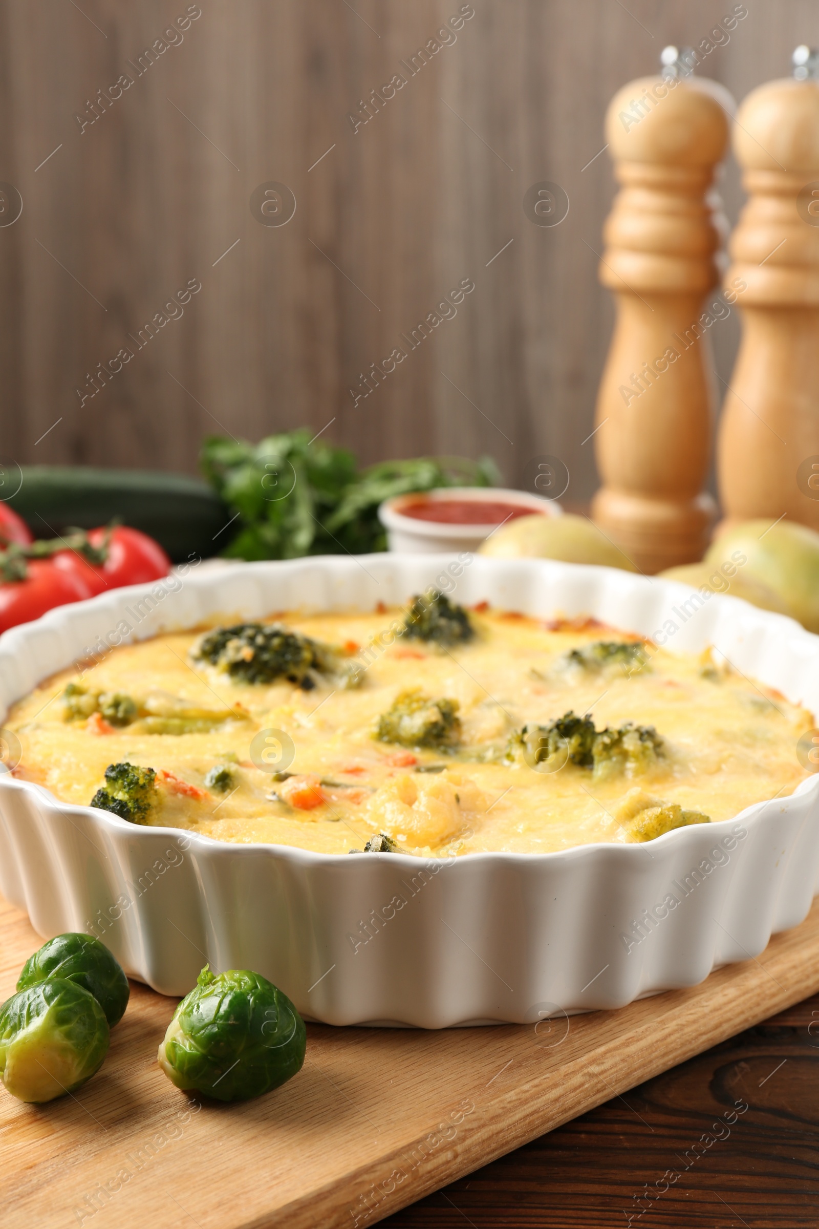 Photo of Delicious vegetable casserole and ingredients on wooden table, closeup