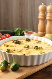 Photo of Delicious vegetable casserole and ingredients on wooden table, closeup