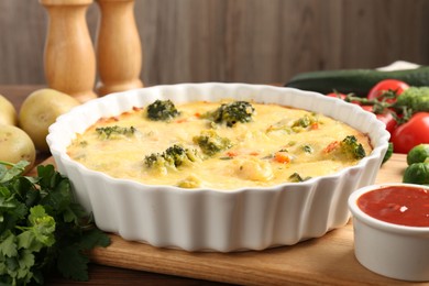 Photo of Delicious vegetable casserole, sauce and ingredients on wooden table, closeup